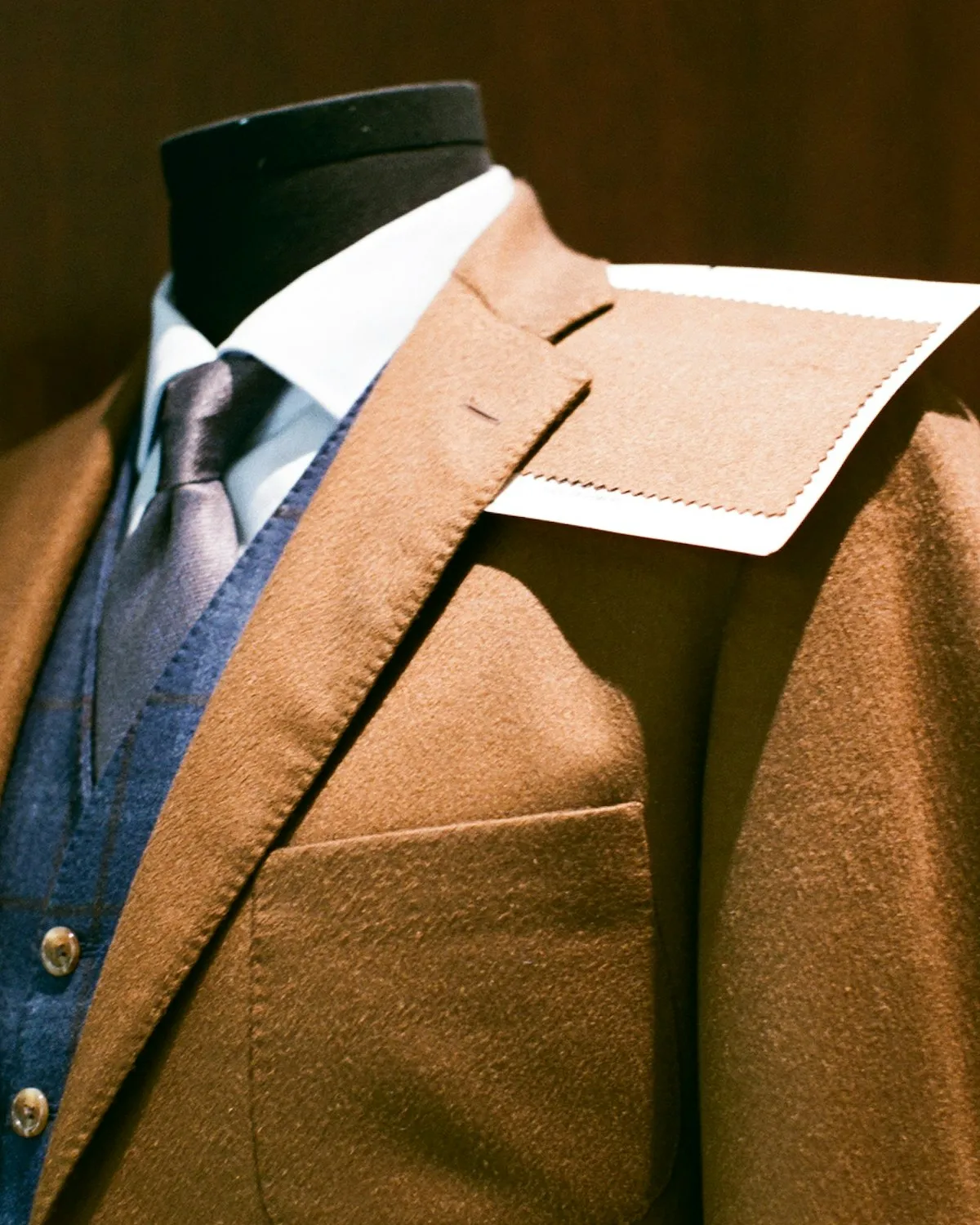 A tailored jacket on a dress form in low studio light.