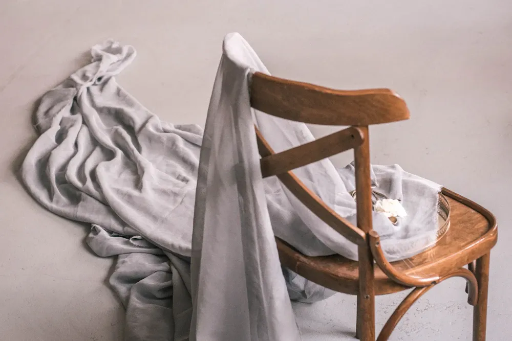 Grey cloth draped over a wooden chair in dim studio light.