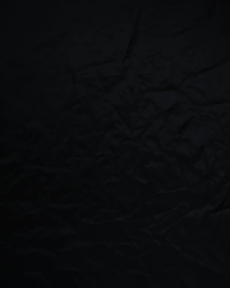 A length of dark cloth spread across a worn wooden table.