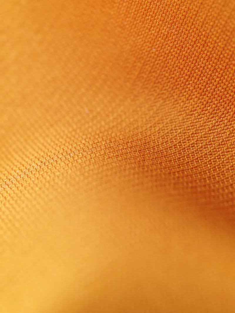 A close weave of dark brown cloth in raking light.